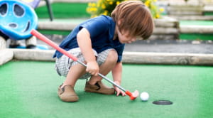 Young child playing mini golf